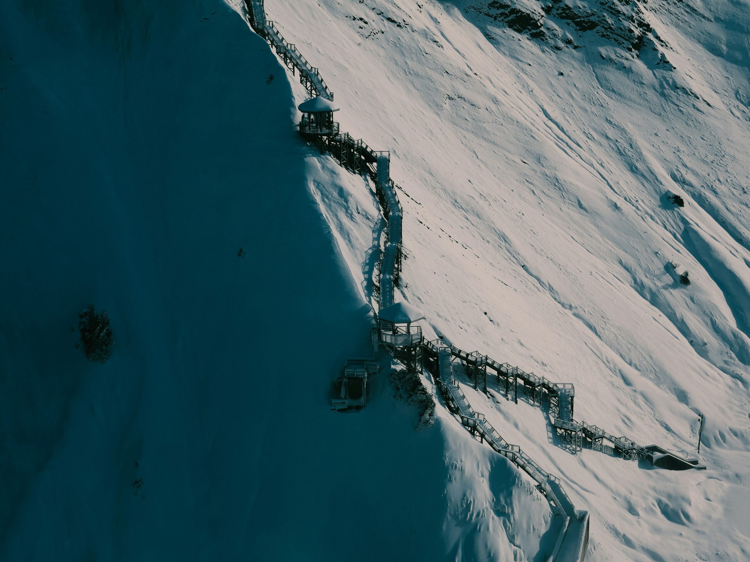 A climber hammering an ice screw piton into a glacier