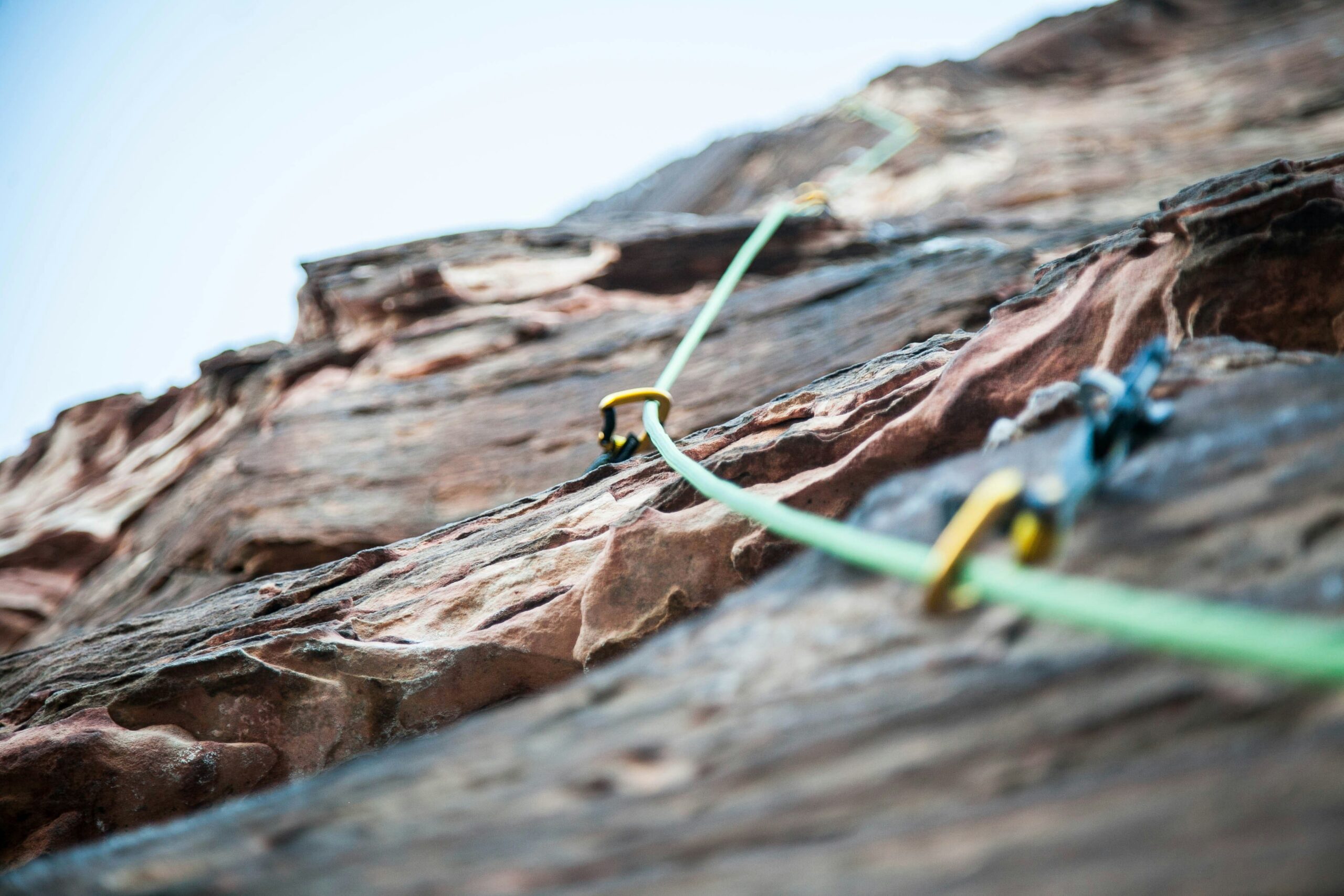 A climber hammering a piton securely into a crack in the rock face.