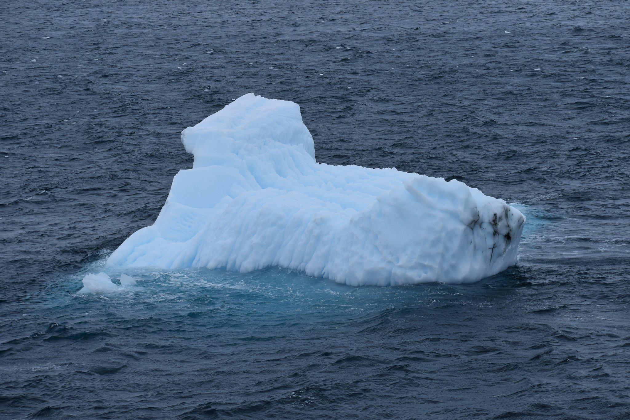 A climber placing tubular ice pitons into an icy cliff face