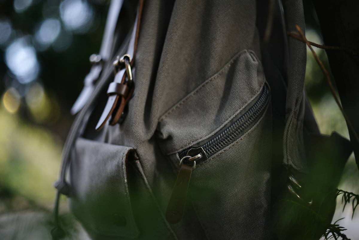 A climber inspecting the sharp edge of a vintage style climbing piton under sunlight.