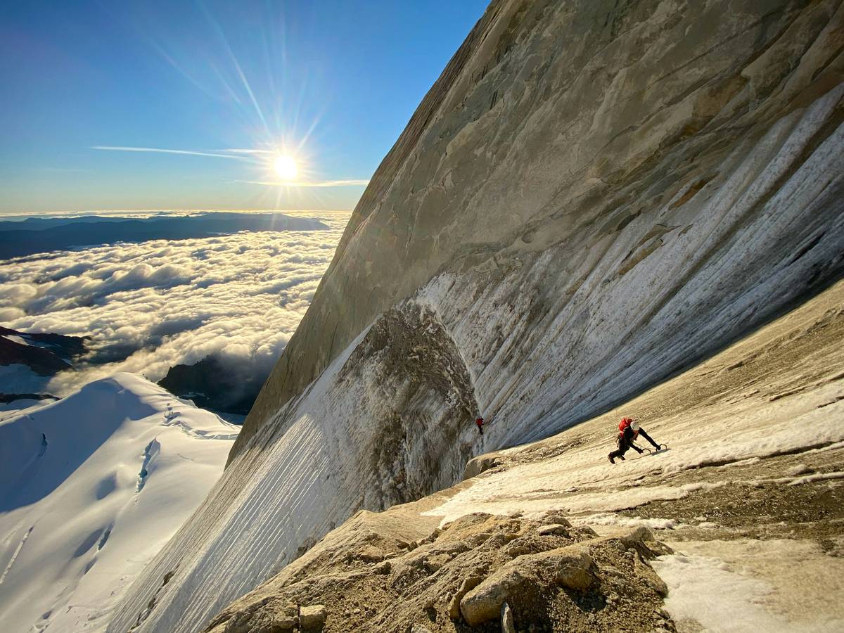 Climber securing themselves with a piton on a snowy mountain face