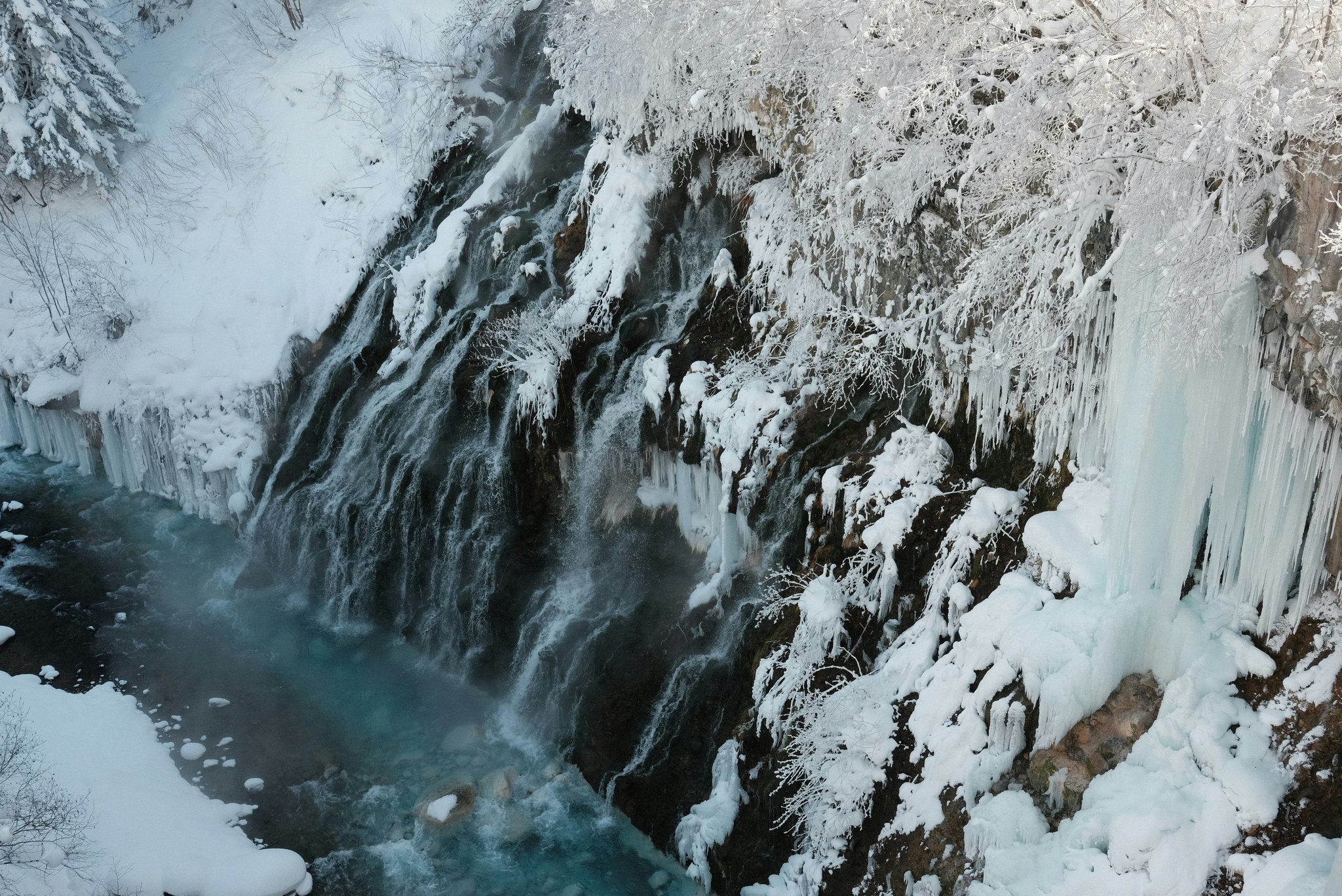 Climbers inspecting their gear setup before ascending a frozen waterfall