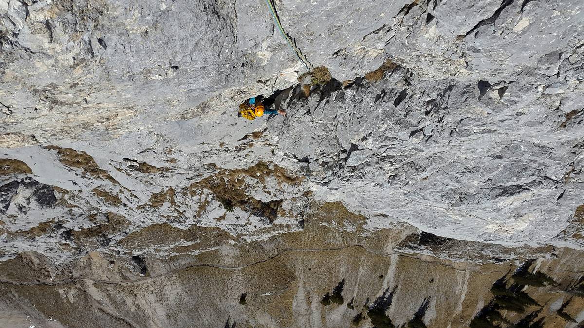 Close-up image of a climber drilling into ice with an ice screw