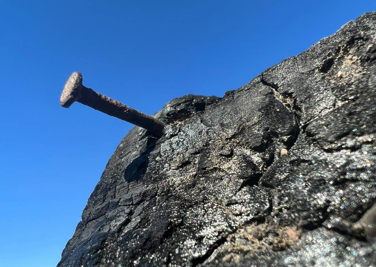 Climber carefully hammering a knifeblade piton into the rock.