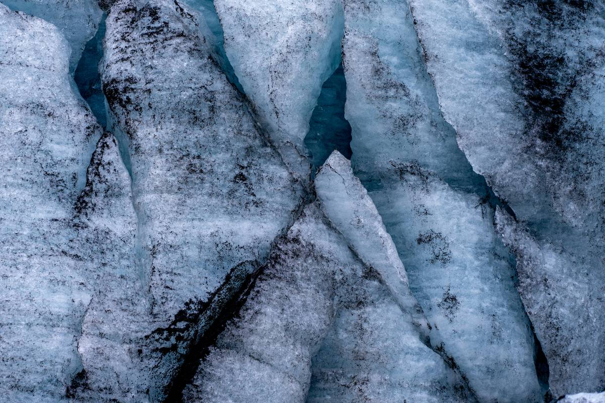 Close-up shot of an ice protection piton embedded in clear blue glacier ice.