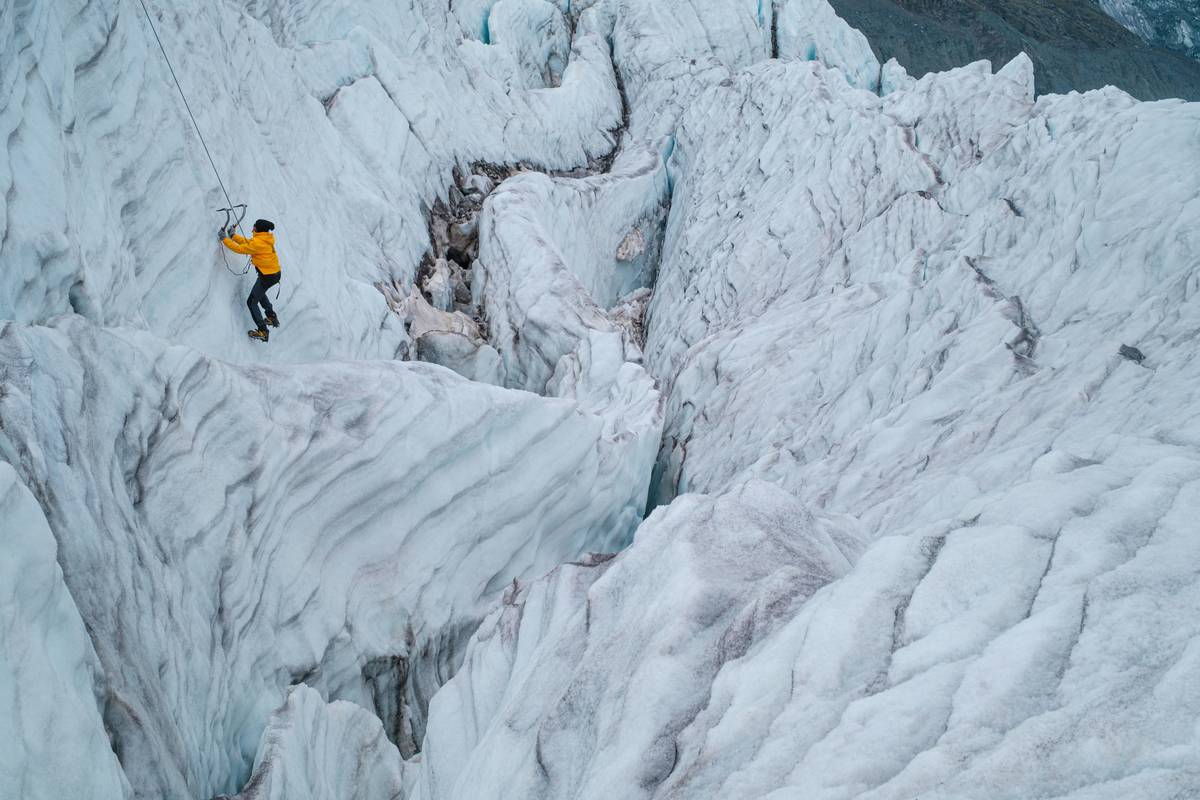 Different types of climbing pitons laid out on an icy surface