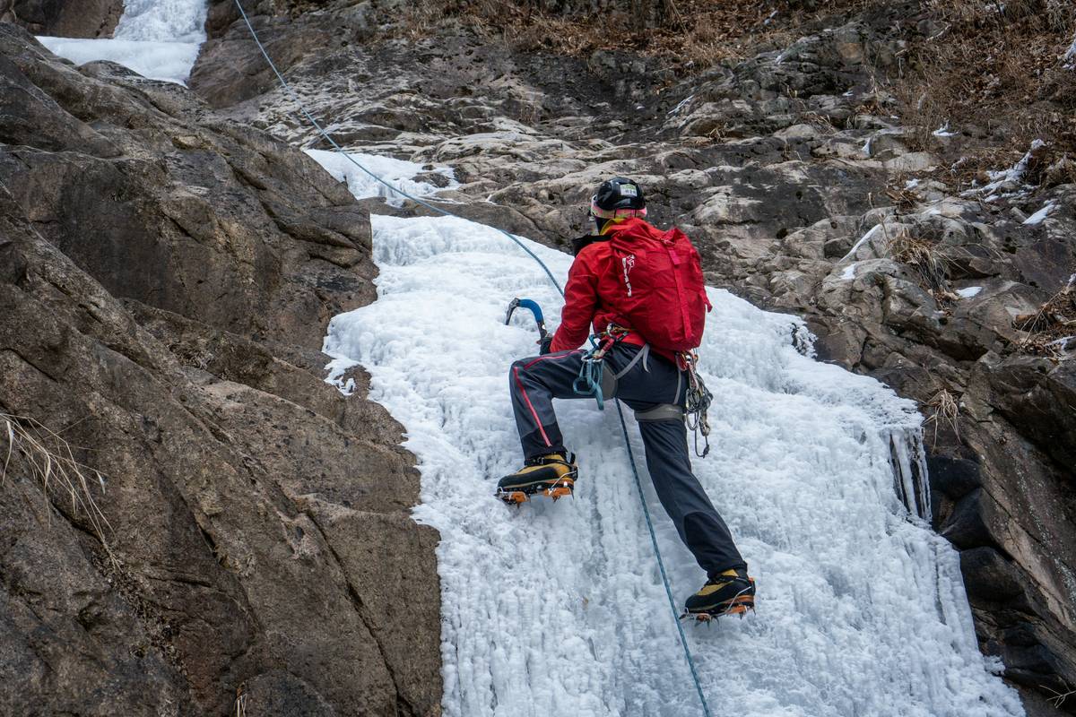 Sarah posing triumphantly atop a frozen waterfall after completing a tough route