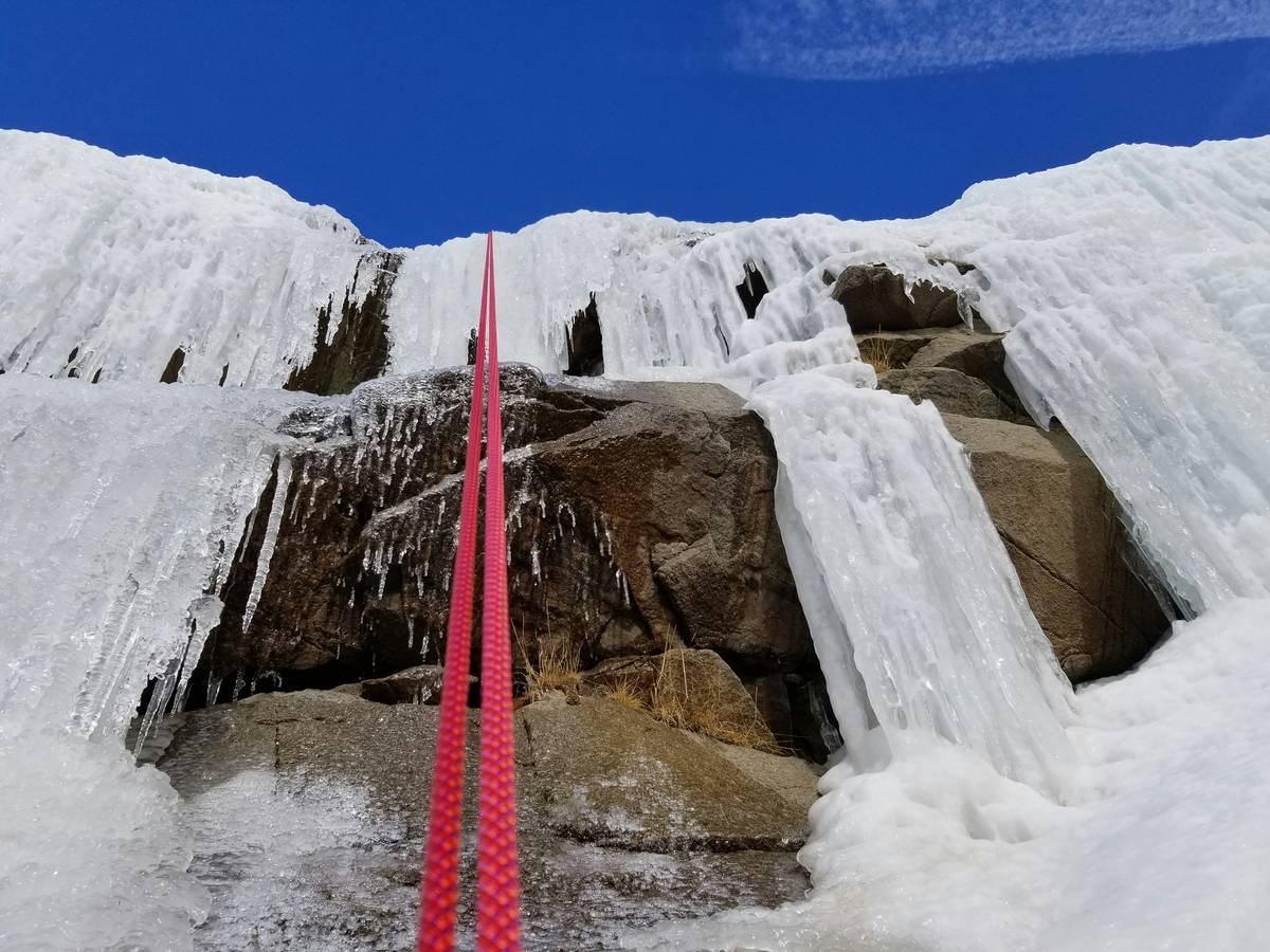 Smiling climber successfully placing a piton in an ice wall