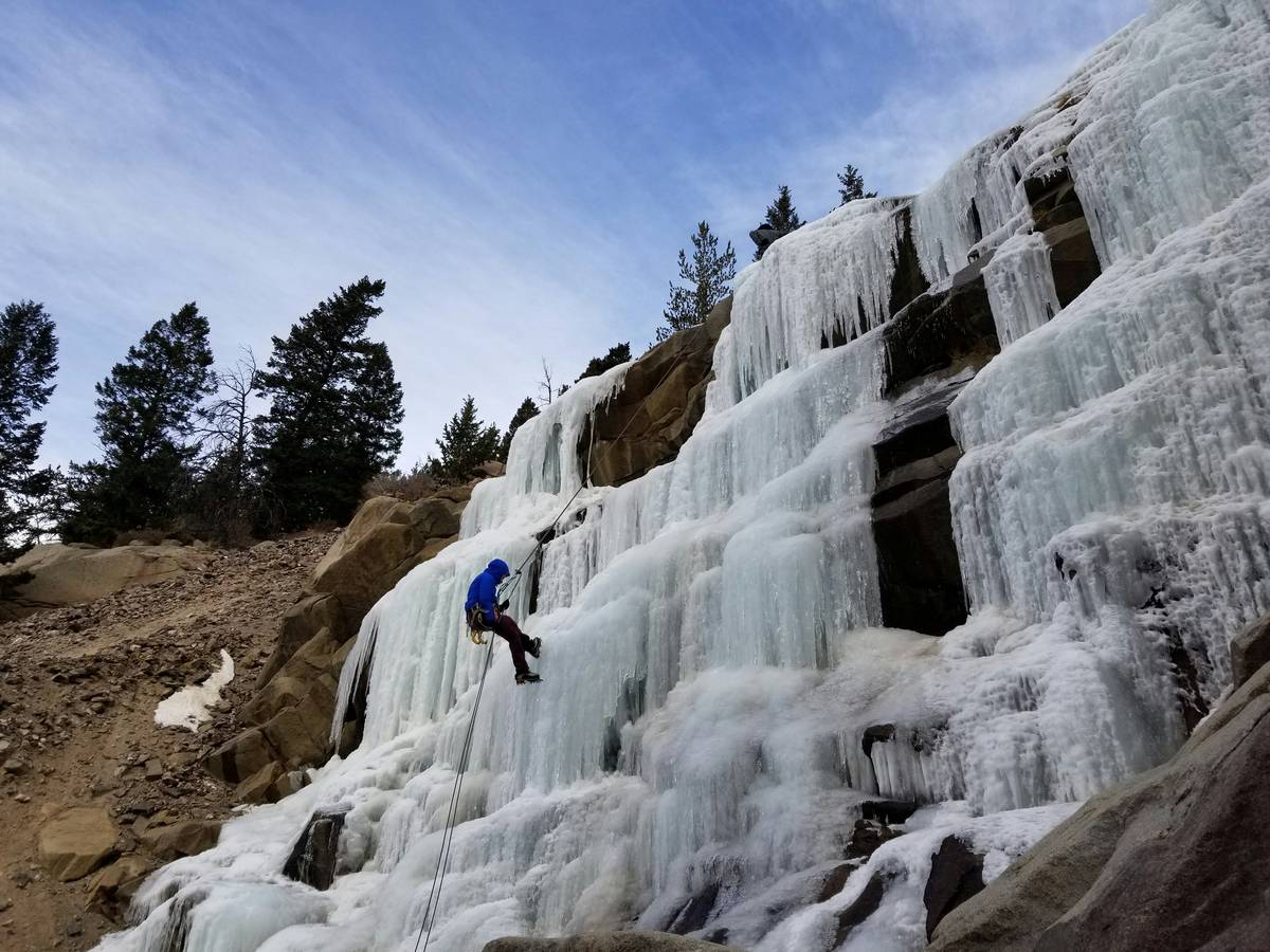 Climber placing a modern ice screw into thick glacier ice.
