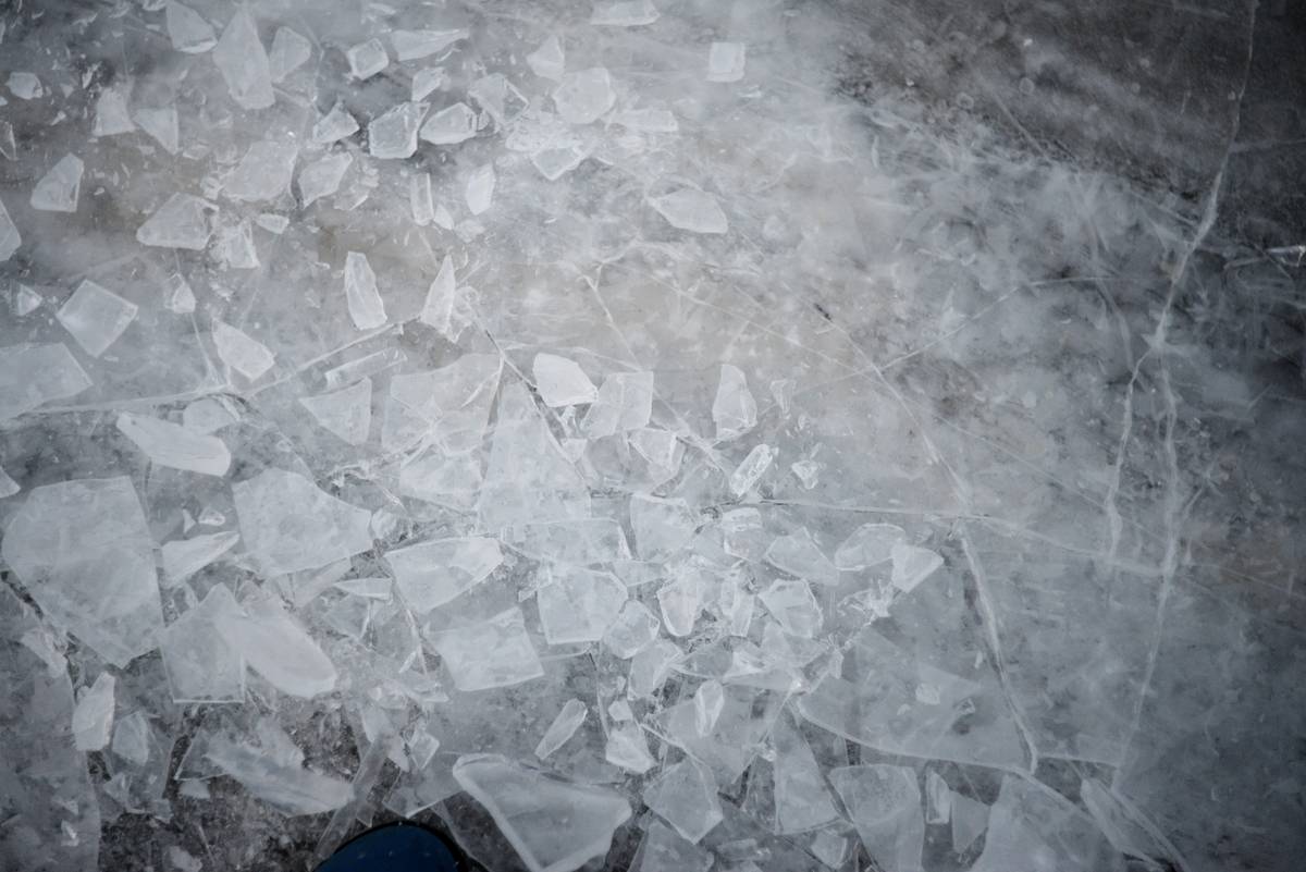 Climber placing an ice piton into a crack in icy rock face