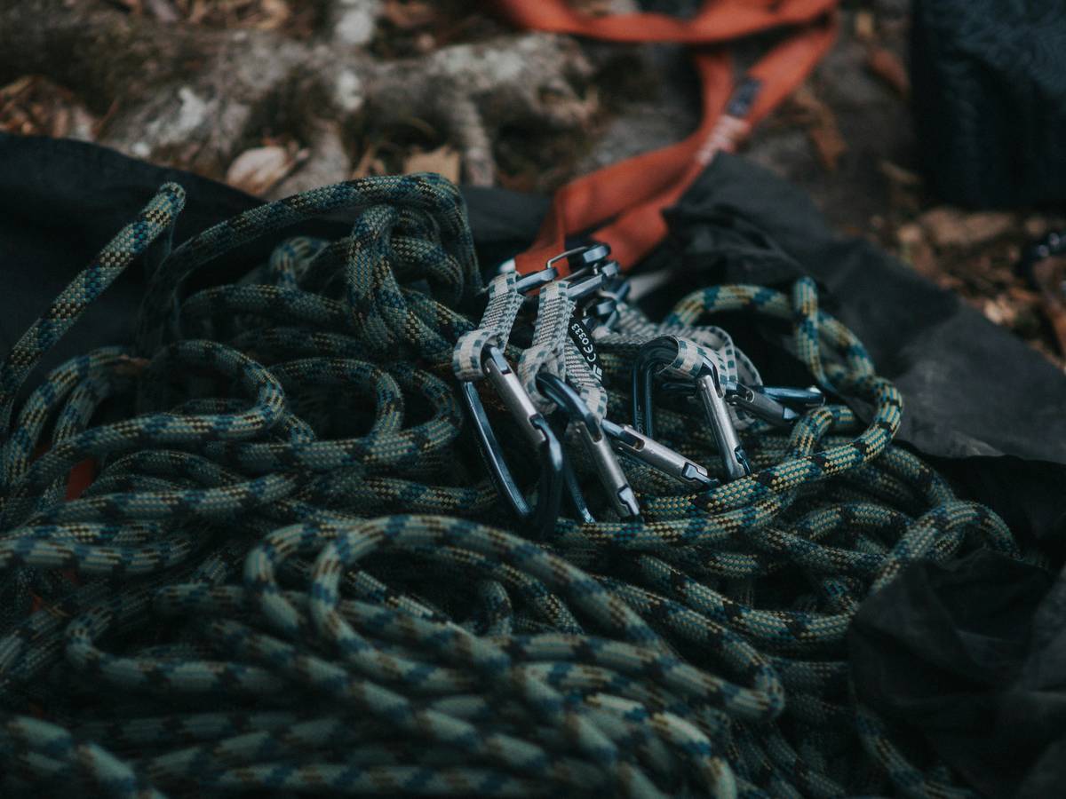 Smiling climber holding well-organized rack against a scenic mountain backdrop