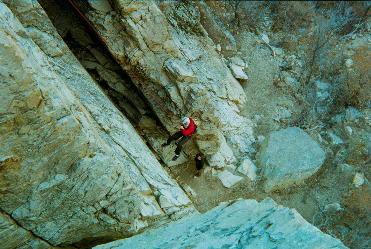 Climber placing a steel piton into rocky terrain