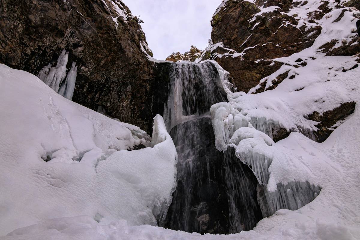 Climber inspecting an installed ice piton while wearing gloves and helmet