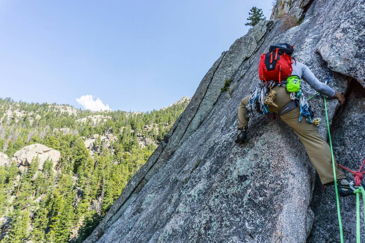 Climber performing an ice piton bend test with a hammer, demonstrating the importance of the test.